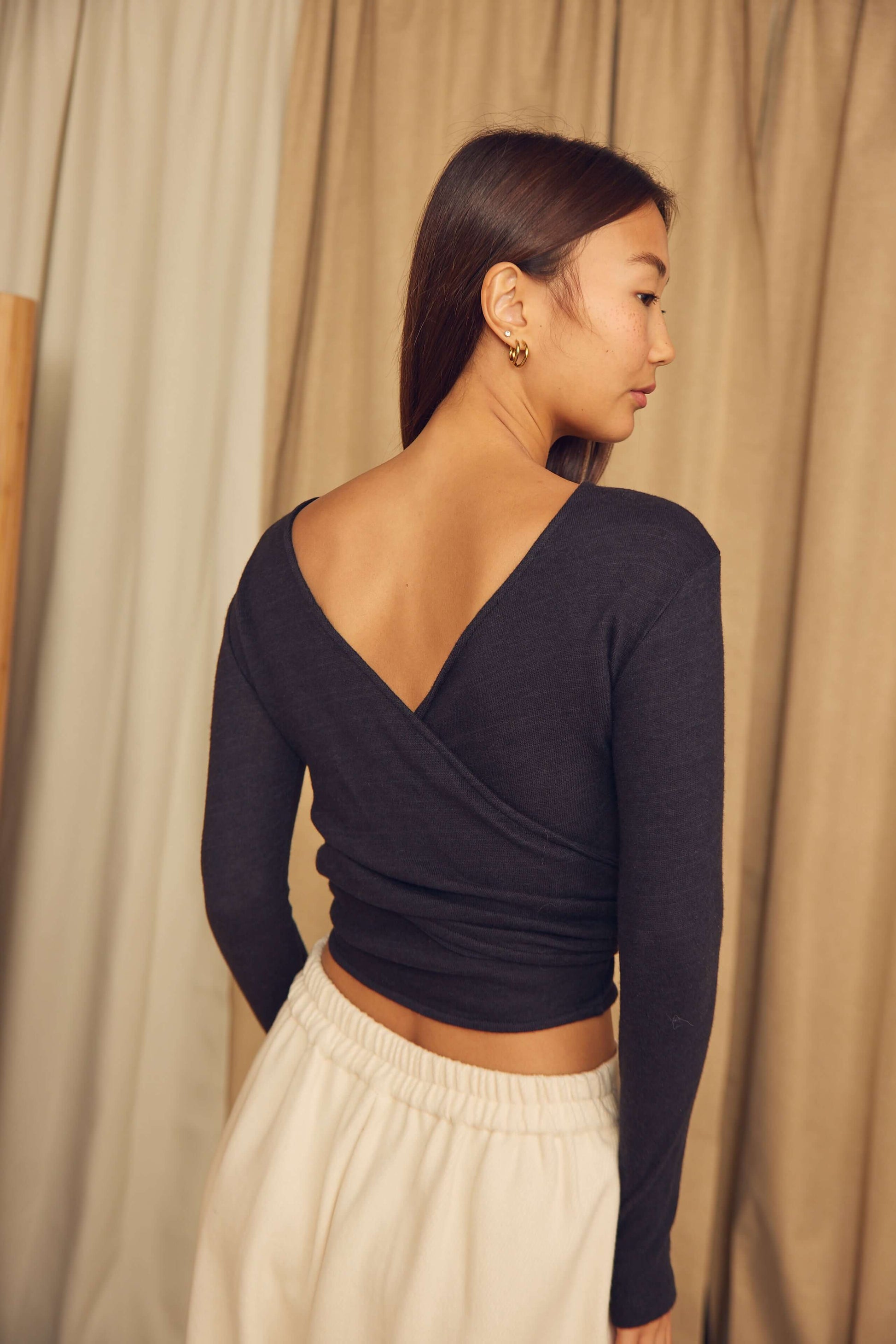 Back view of a model wearing a Black Wool Wrap Top with thumb holes, showcasing the unique wrap design.
