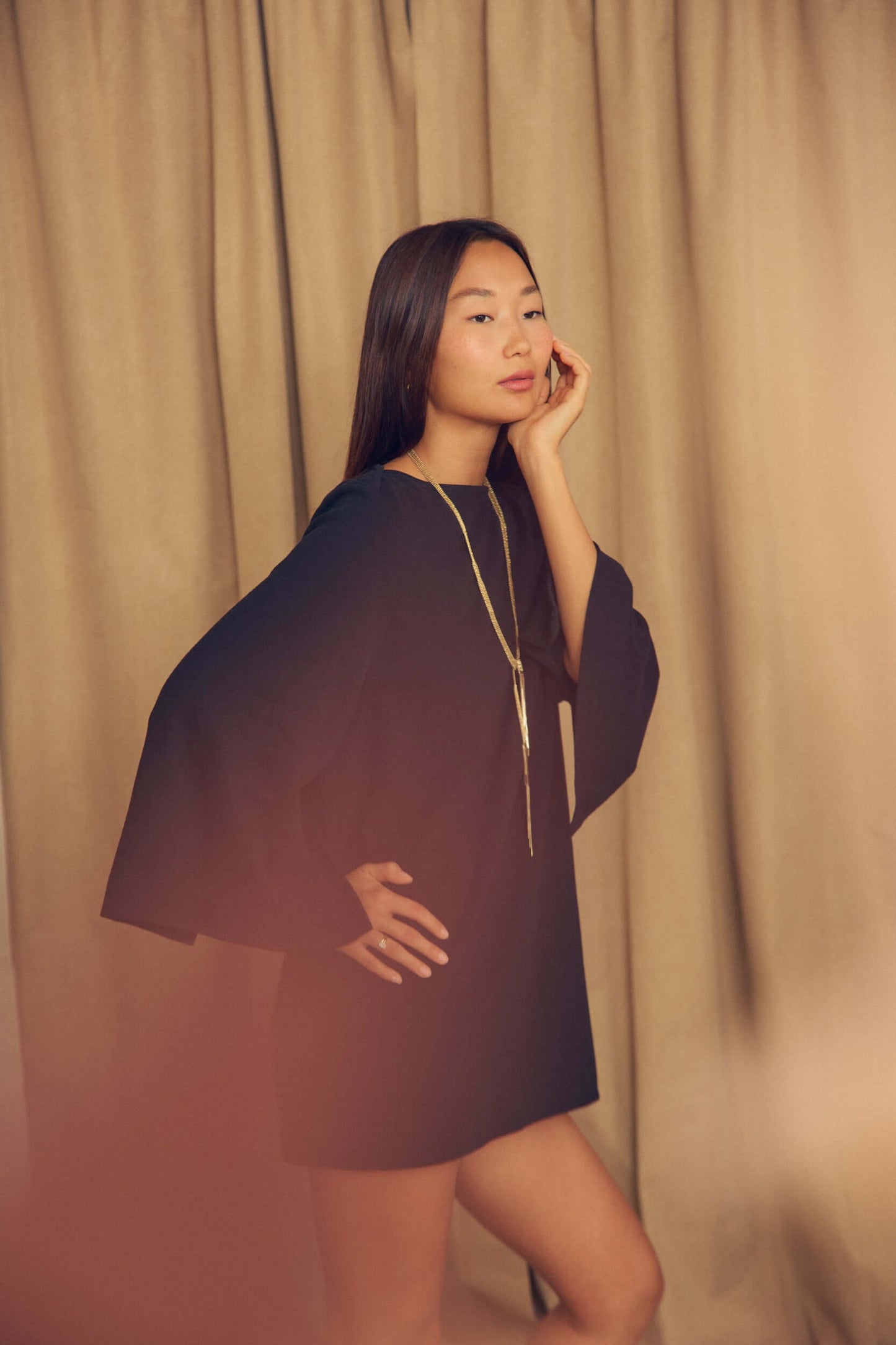 Model wearing a Black Organic Cotton Mini Dress with Flared Sleeves, showcasing its elegant design and flared sleeves.