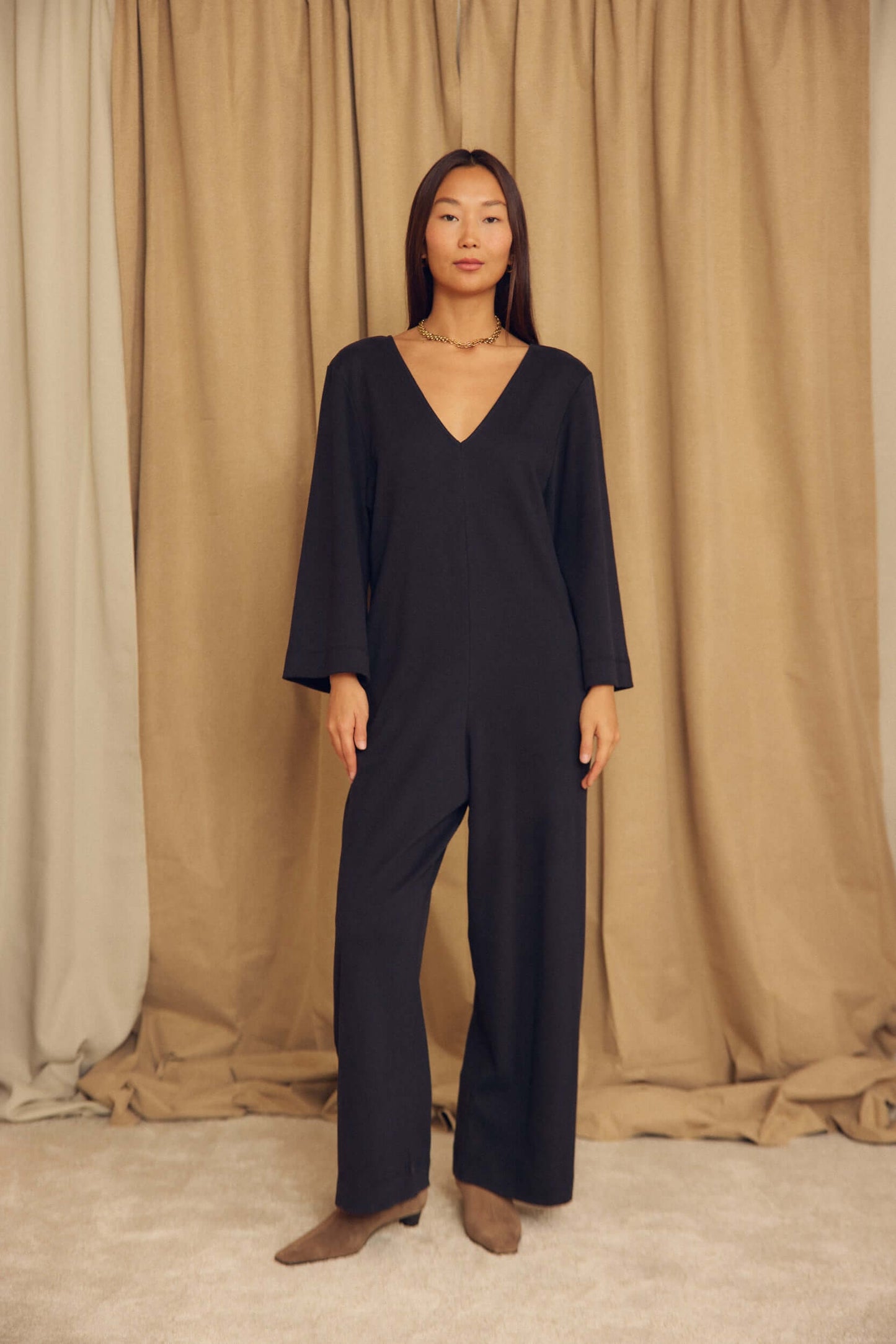 Black Organic Cotton Wide-Leg Jumpsuit on model with flared sleeves and wide legs, set against a neutral background.