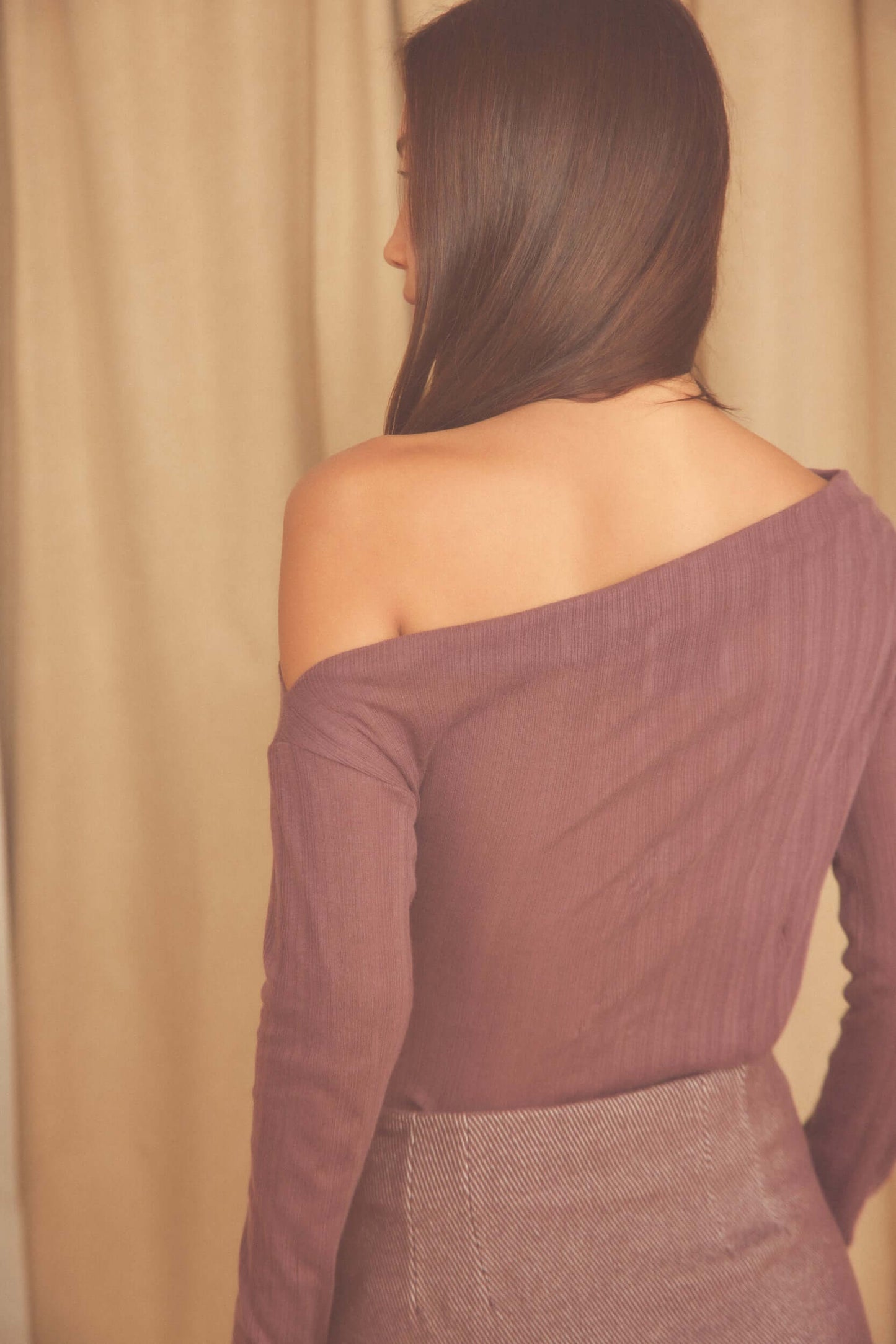 Back view of a model wearing the Cocoa Lyocell Ribbed Drape Bodysuit in soft cocoa brown.