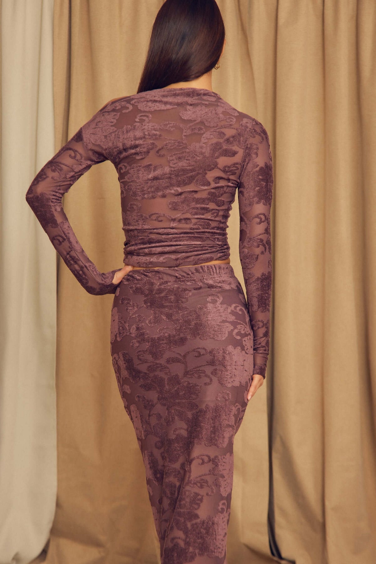 Back view of a woman wearing the Cocoa Devoré Fitted Midi Skirt with a matching long-sleeved top in a textured design.