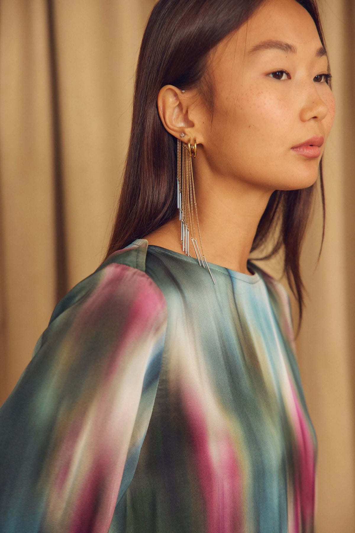 Close-up of a model wearing a Printed ECOVERO Viscose Mini Dress with Flared Sleeves and statement earrings.