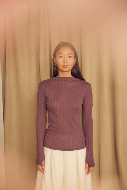 Model wearing Cocoa Lyocell Ribbed Long Sleeve Top in rich purple against soft backdrop.