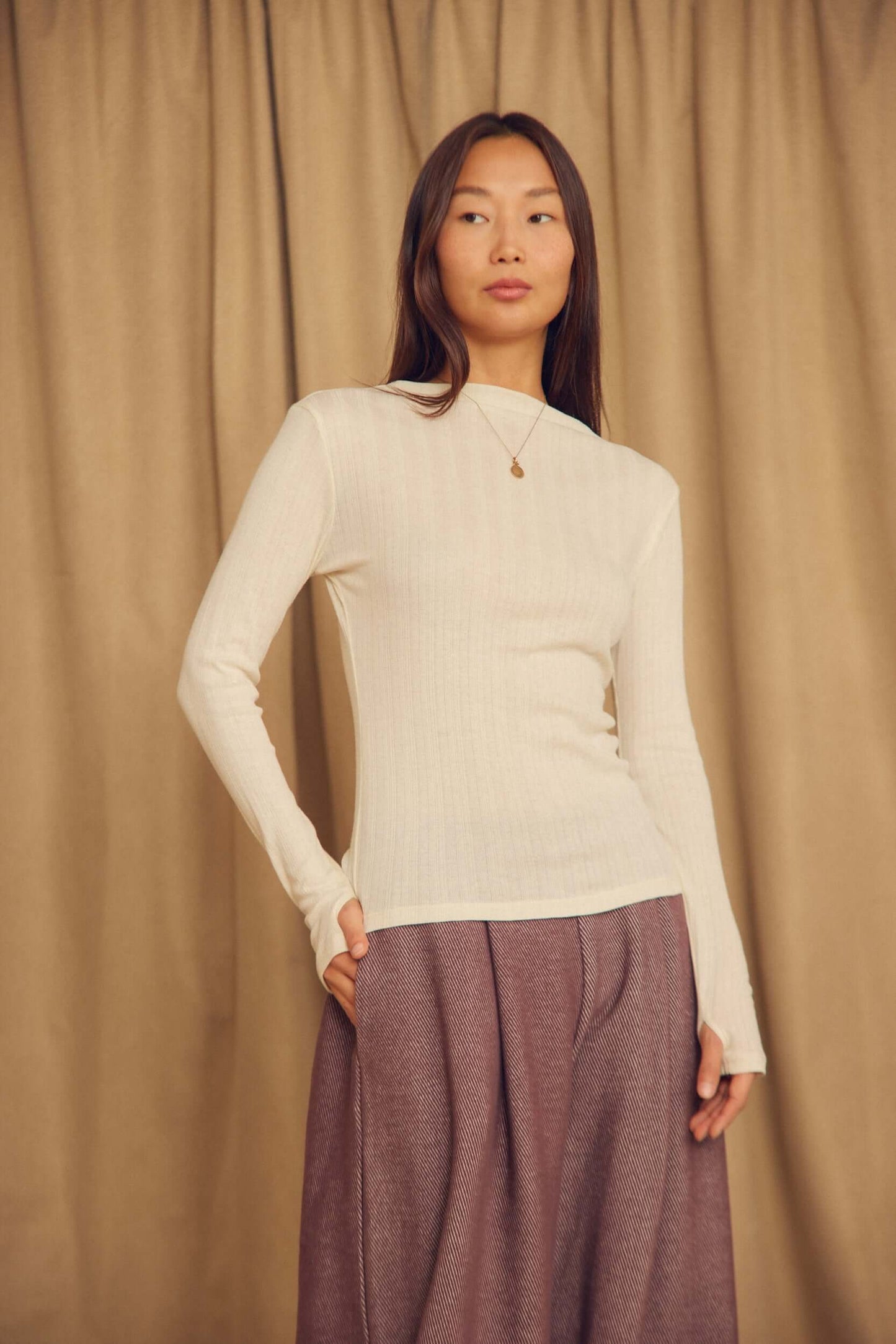 Ecru Lyocell Ribbed Long Sleeve Top modeled by a woman in a neutral setting, highlighting its soft ribbed texture.