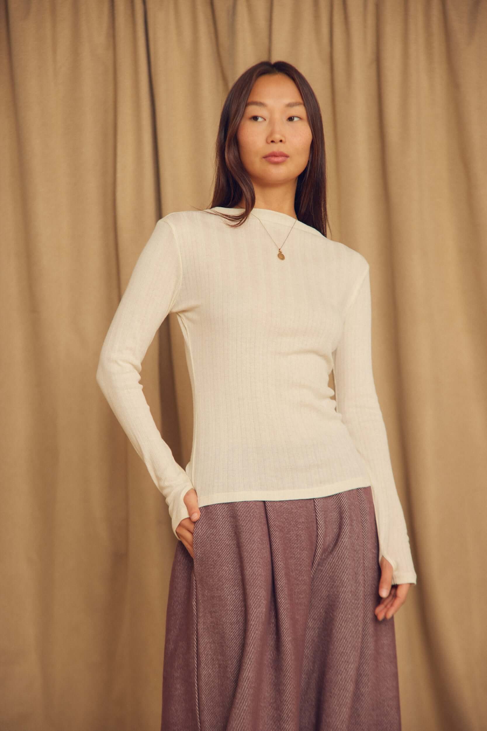 Ecru Lyocell Ribbed Long Sleeve Top modeled by a woman in a neutral setting, highlighting its soft ribbed texture.