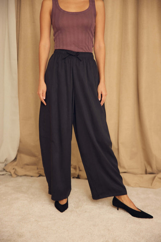 Model wearing Black Lyocell Barrel-Leg Trousers with a fitted top and heels, showcasing relaxed tailoring style.