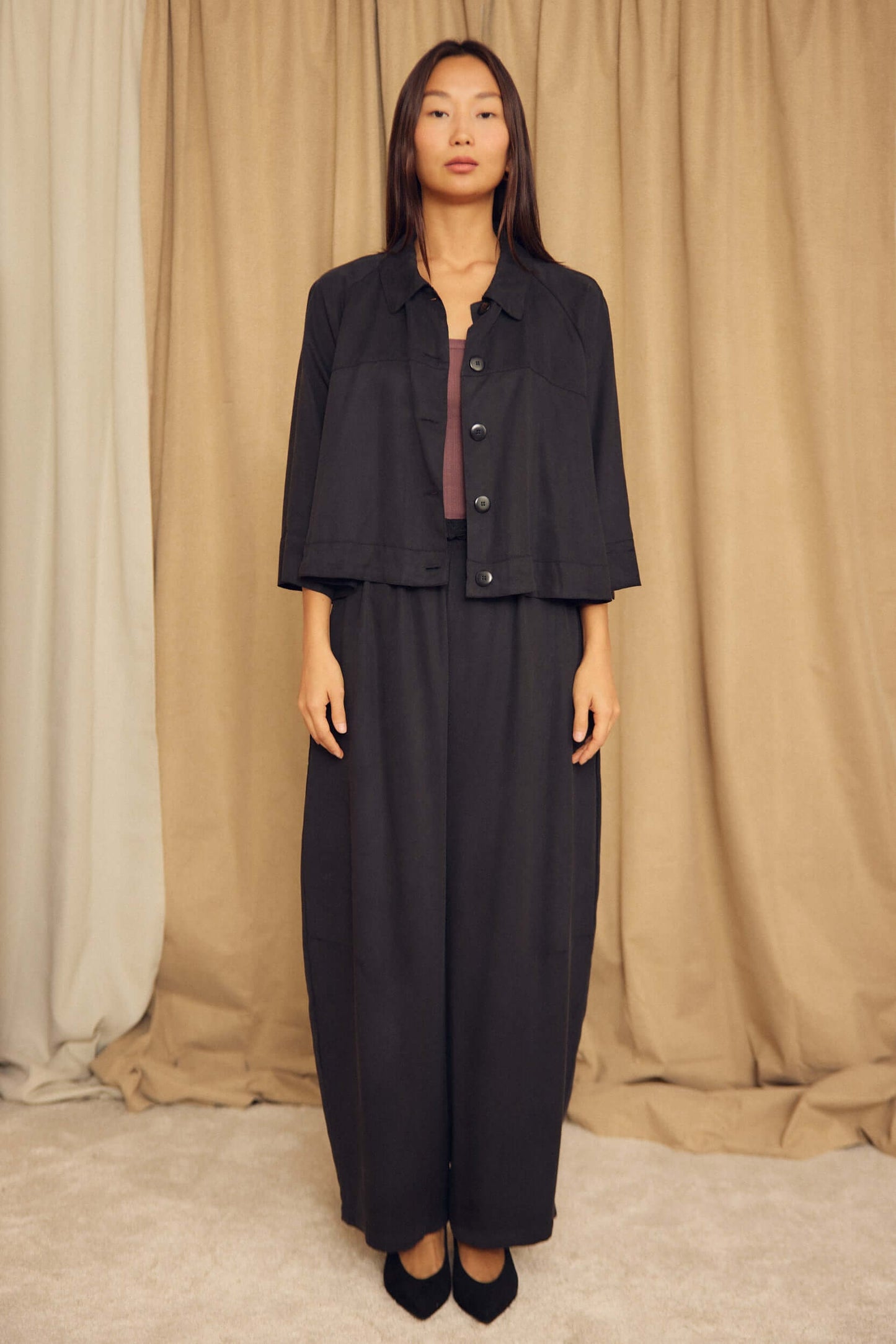 Model wearing Black Lyocell Barrel-Leg Trousers paired with a matching cropped jacket on a neutral background.