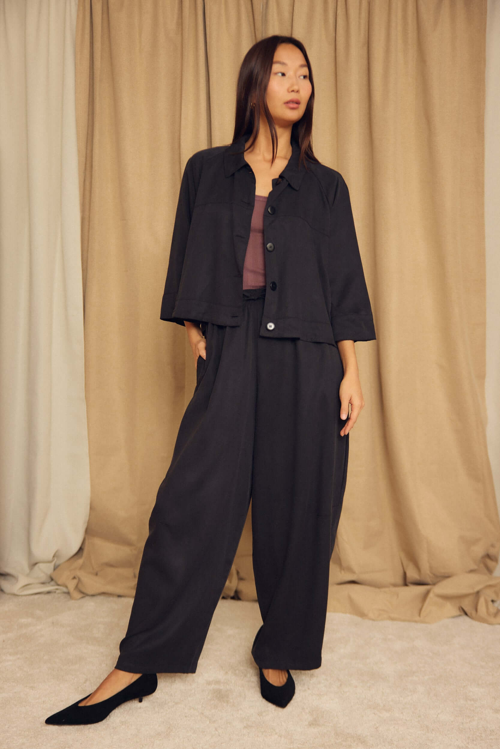 Model wearing Black Lyocell Barrel-Leg Trousers paired with a stylish cropped jacket on a soft background.