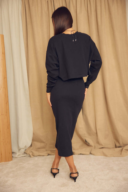 Back view of a person wearing a Black Organic Cotton Oversized Crop Top paired with a fitted skirt.