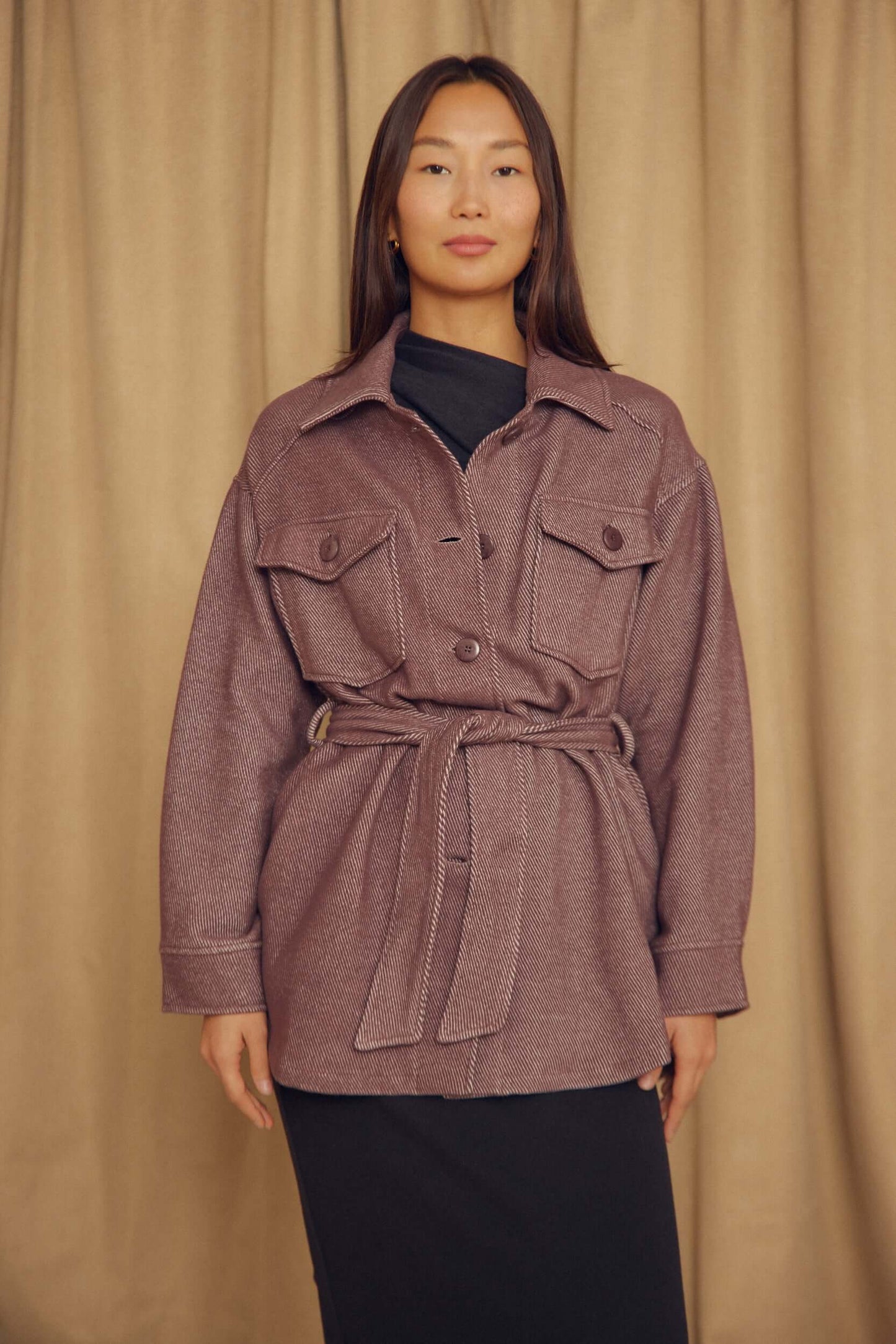Model wearing Cocoa Organic Cotton Shacket with a belt over a black dress, styled against a neutral backdrop.