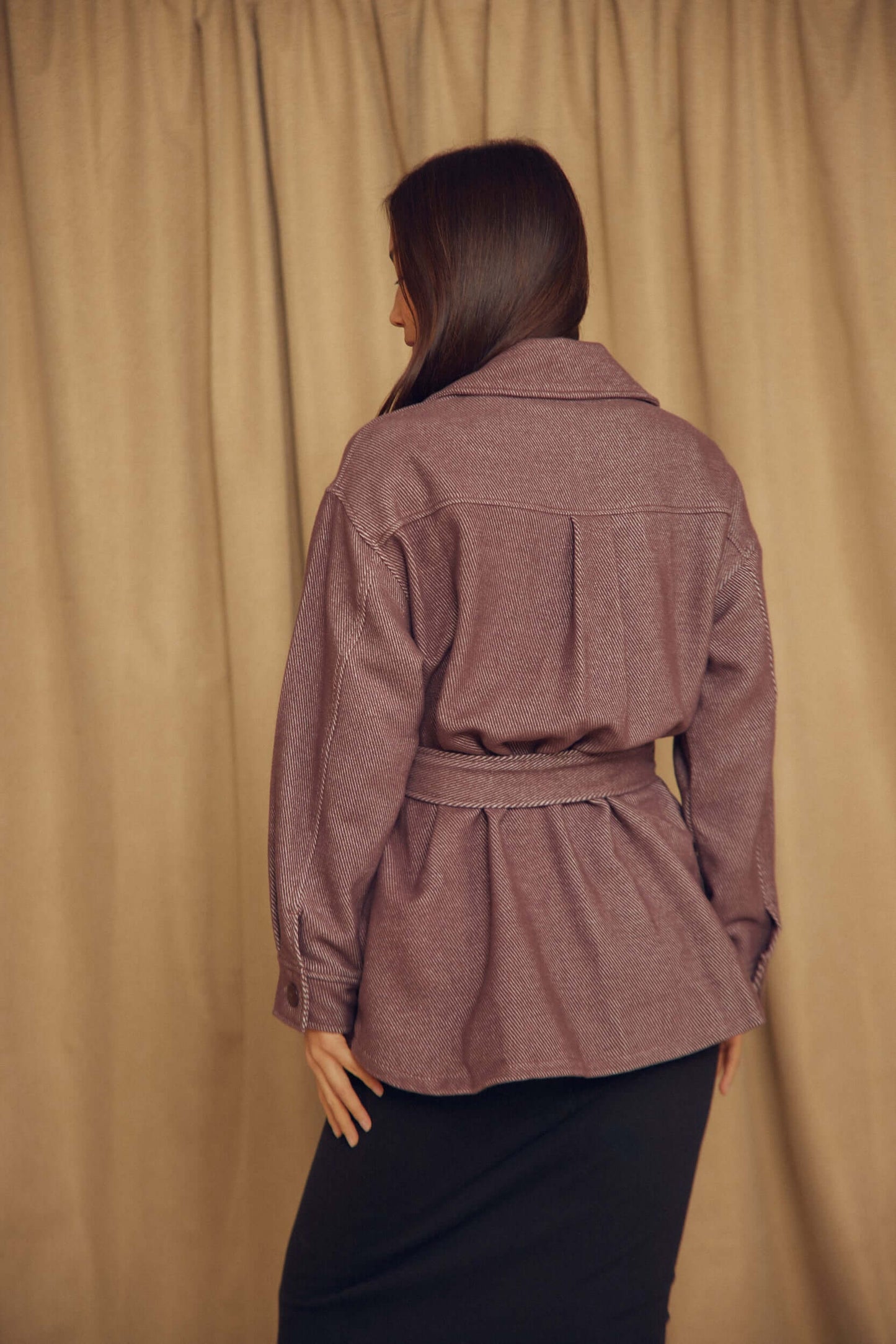 Back view of a woman wearing a Cocoa Organic Cotton Shacket with a belt, showcasing its relaxed silhouette.