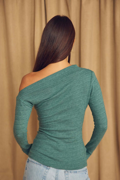 Back view of a woman wearing a Teal Wool Drape Top with thumb holes against a soft fabric background.