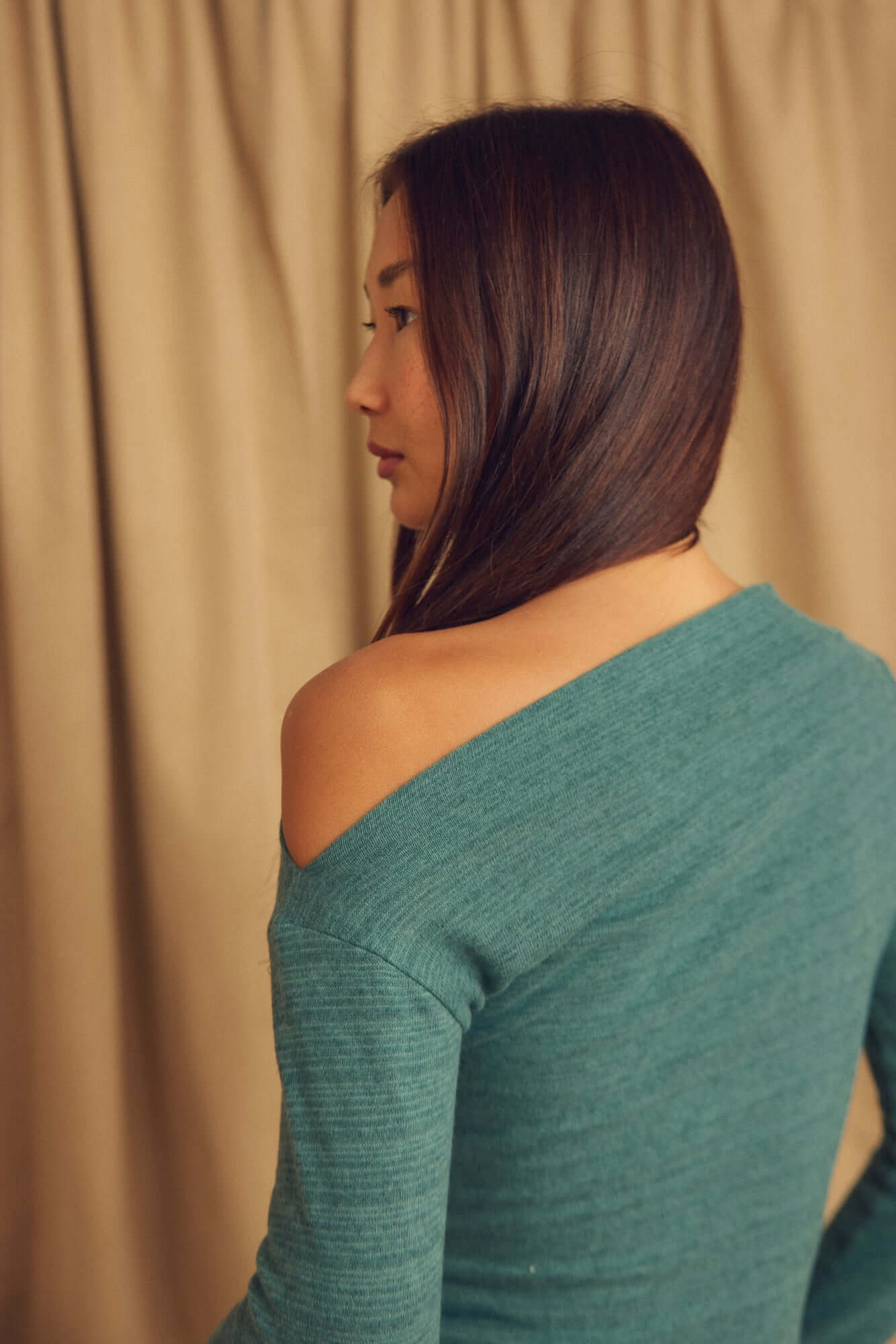 Model wearing the Teal Wool Drape Top with thumb holes, showcasing the elegant draped neckline from the back.