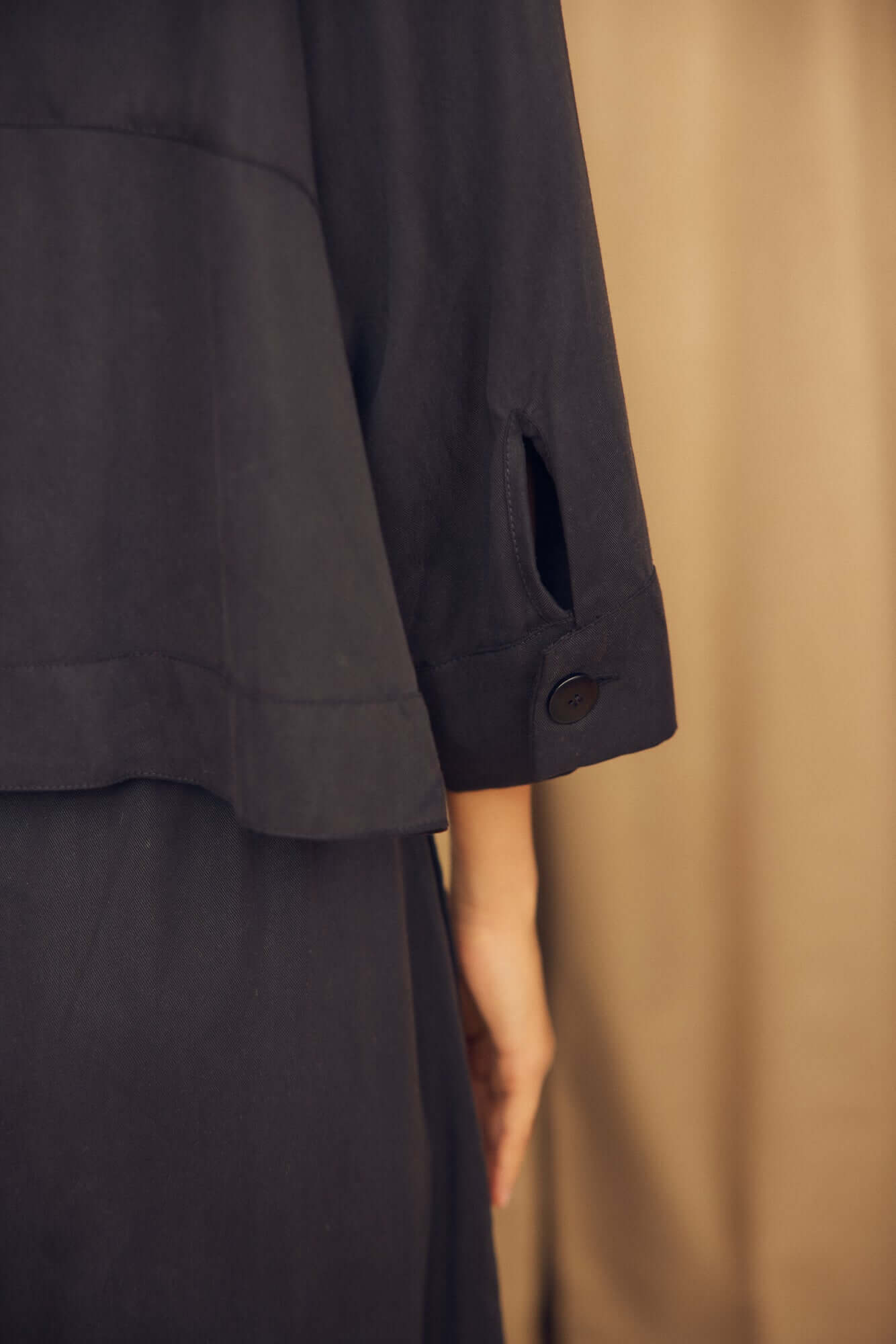 Black Lyocell Flared Jacket showcasing its elegant flared sleeve and eco corozo button detail.