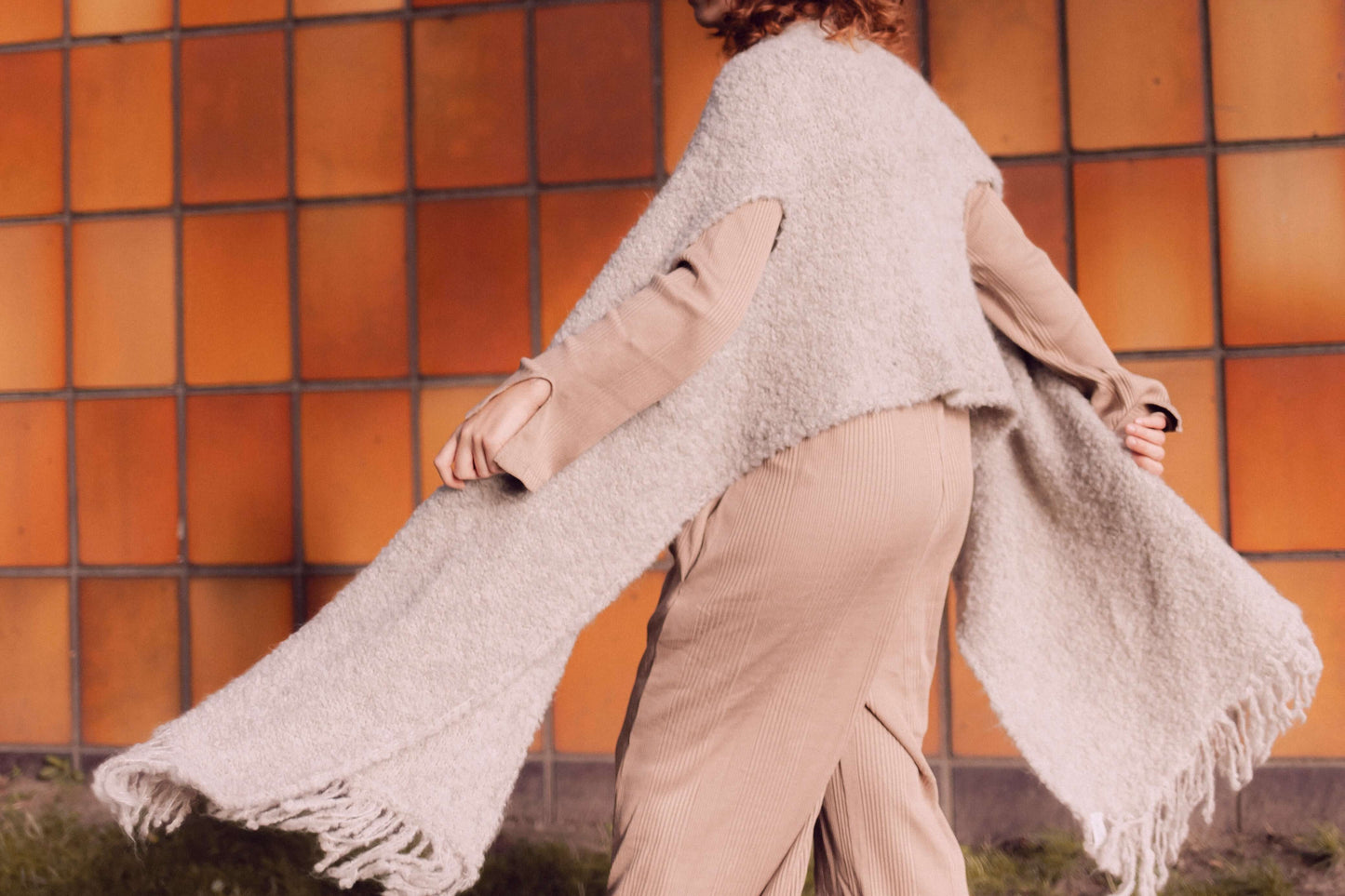 Woman wearing versatile grey poncho scarf made from sustainable alpaca and recycled polyester, showcasing stylish fall fashion.