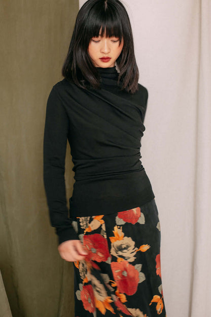 Woman wearing black drape knit top from Porto fine lyocell & cotton jersey blend, paired with floral skirt.