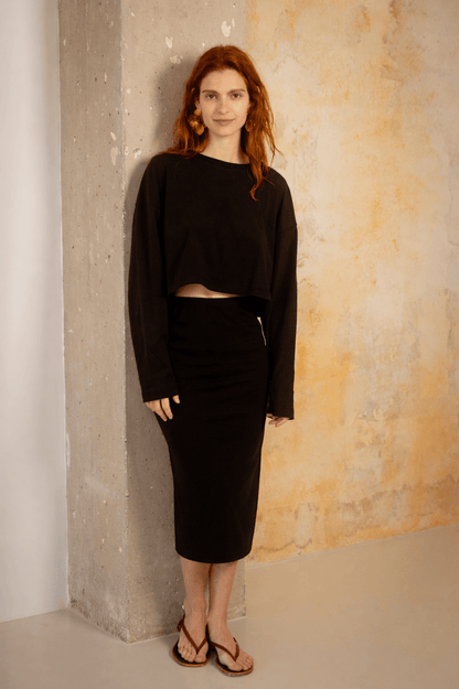 Model wearing an Organic Cotton Long Sleeve Top in Black with a matching skirt, showcasing a relaxed and stylish look.