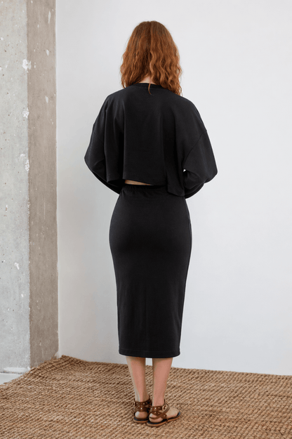 Model wearing Organic Cotton Long Sleeve Top in Black, showcasing the back view with a relaxed fit and oversized silhouette.