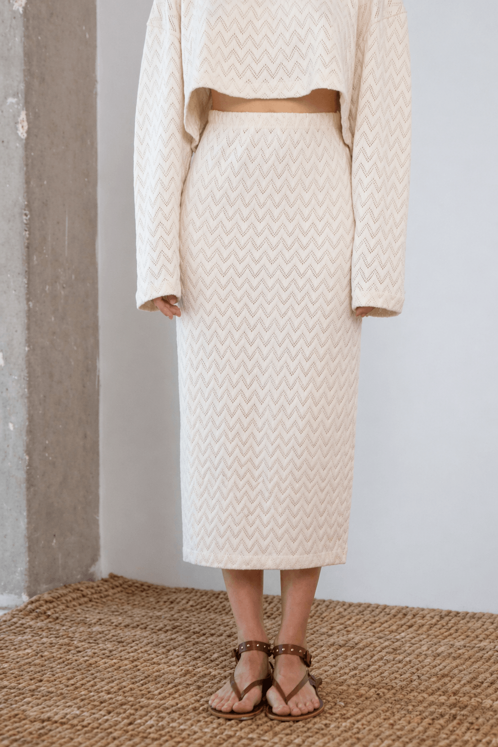 Model wearing a Crochet Organic Cotton Midi Skirt in ecru, showcasing its textured and elegant design.
