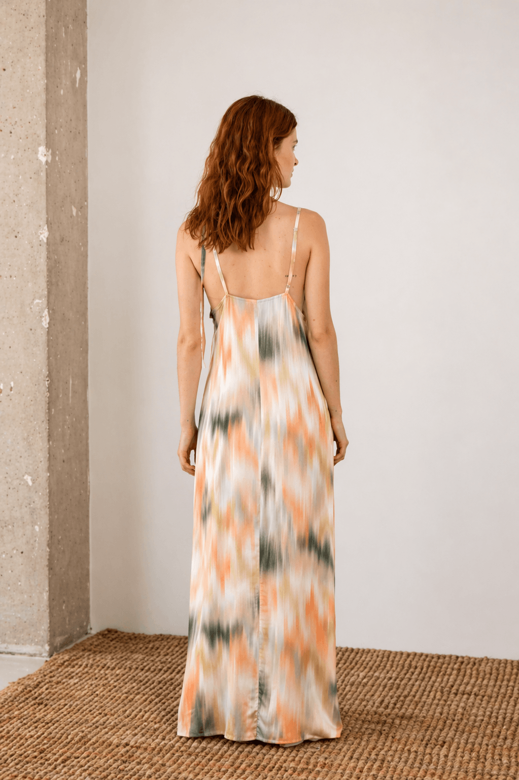 Back view of a woman wearing a Printed Ecovero Viscose Maxi Dress with adjustable straps and a colorful print.