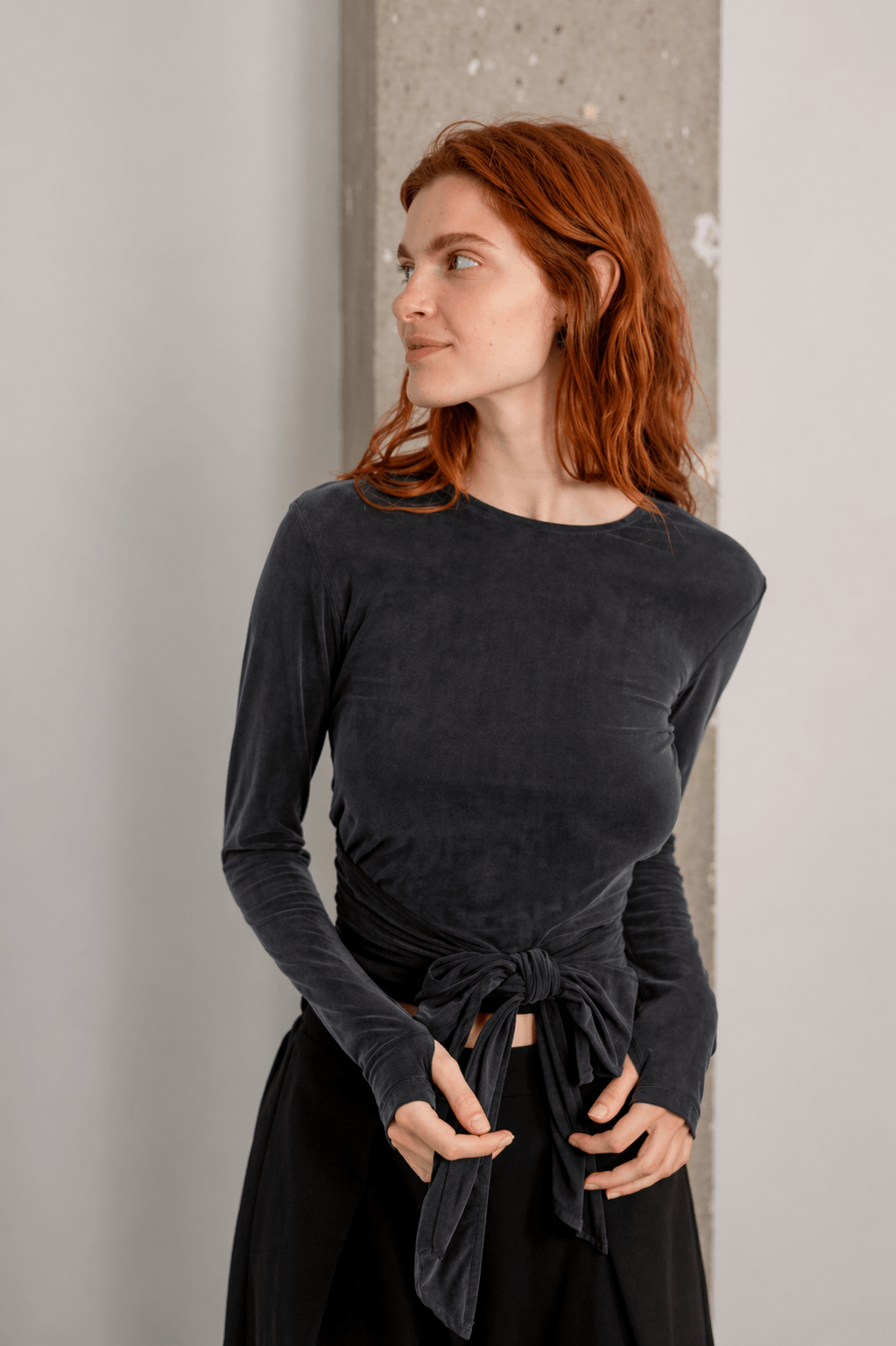 Woman wearing Cupro Multiway Wrap Top in Slate Black with a stylish tied detail.