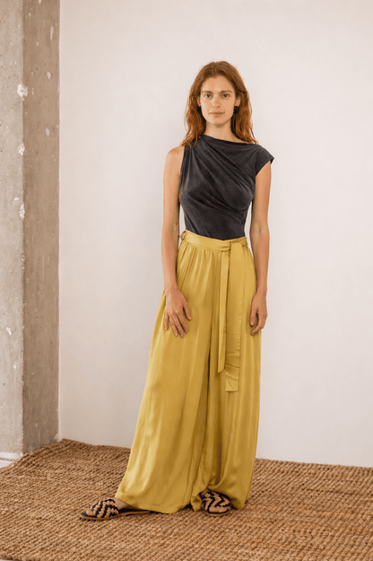 Drape Neckline Bodysuit in Slate Black paired with yellow flowy trousers, showcasing modern styling in a minimalist setting.