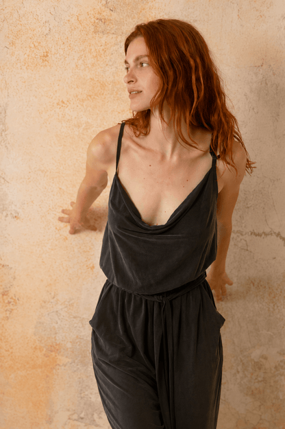 Cupro Slip Jumpsuit with Belt in Slate Black on a model against a textured background.