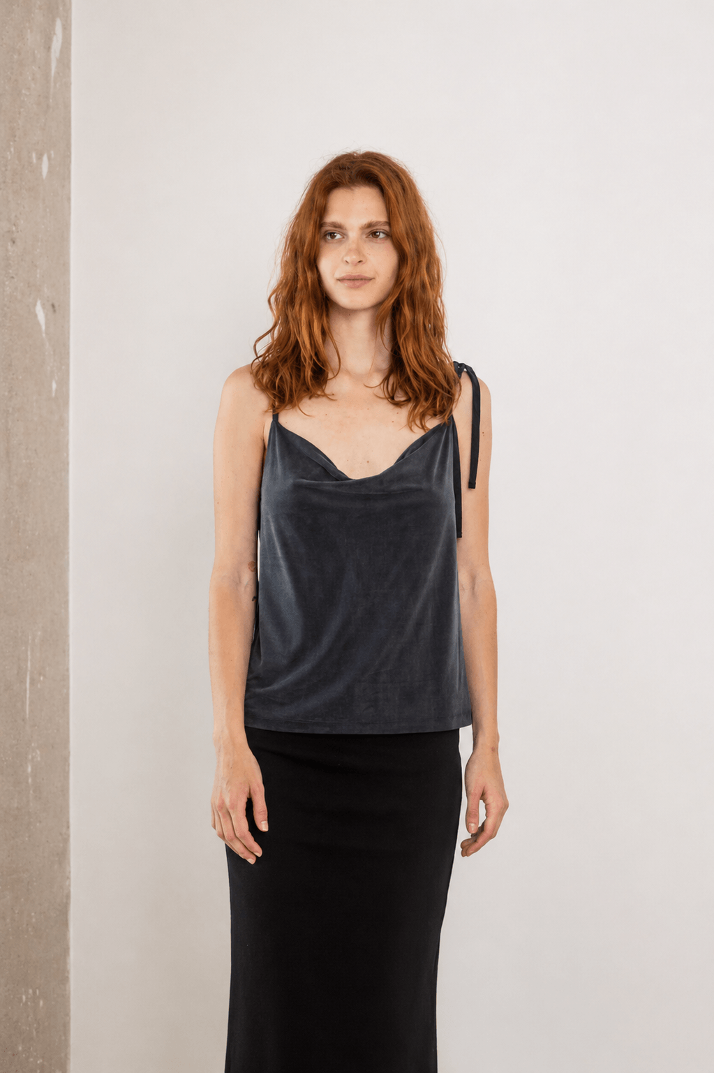 Model wearing Cupro Drape Slip Top in Soft Olive paired with a black skirt, showcasing elegant everyday style.