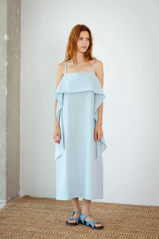 Organic Cotton Sun Dress with Front Frill in Pale Blue worn by a model in a bright setting.