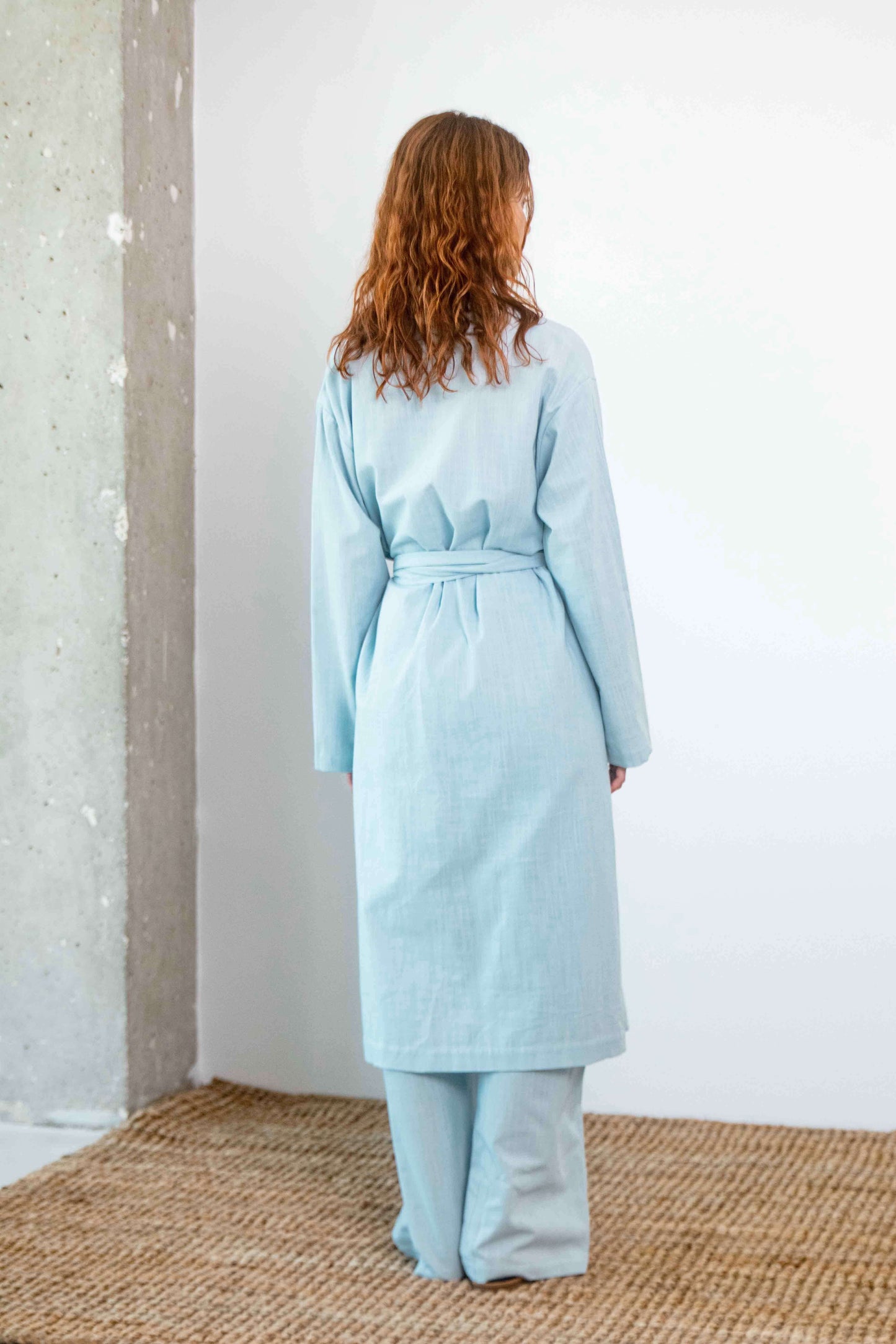 Lightweight Organic Cotton Trench Coat in Pale Blue displayed from the back, featuring a relaxed silhouette and detachable belt.