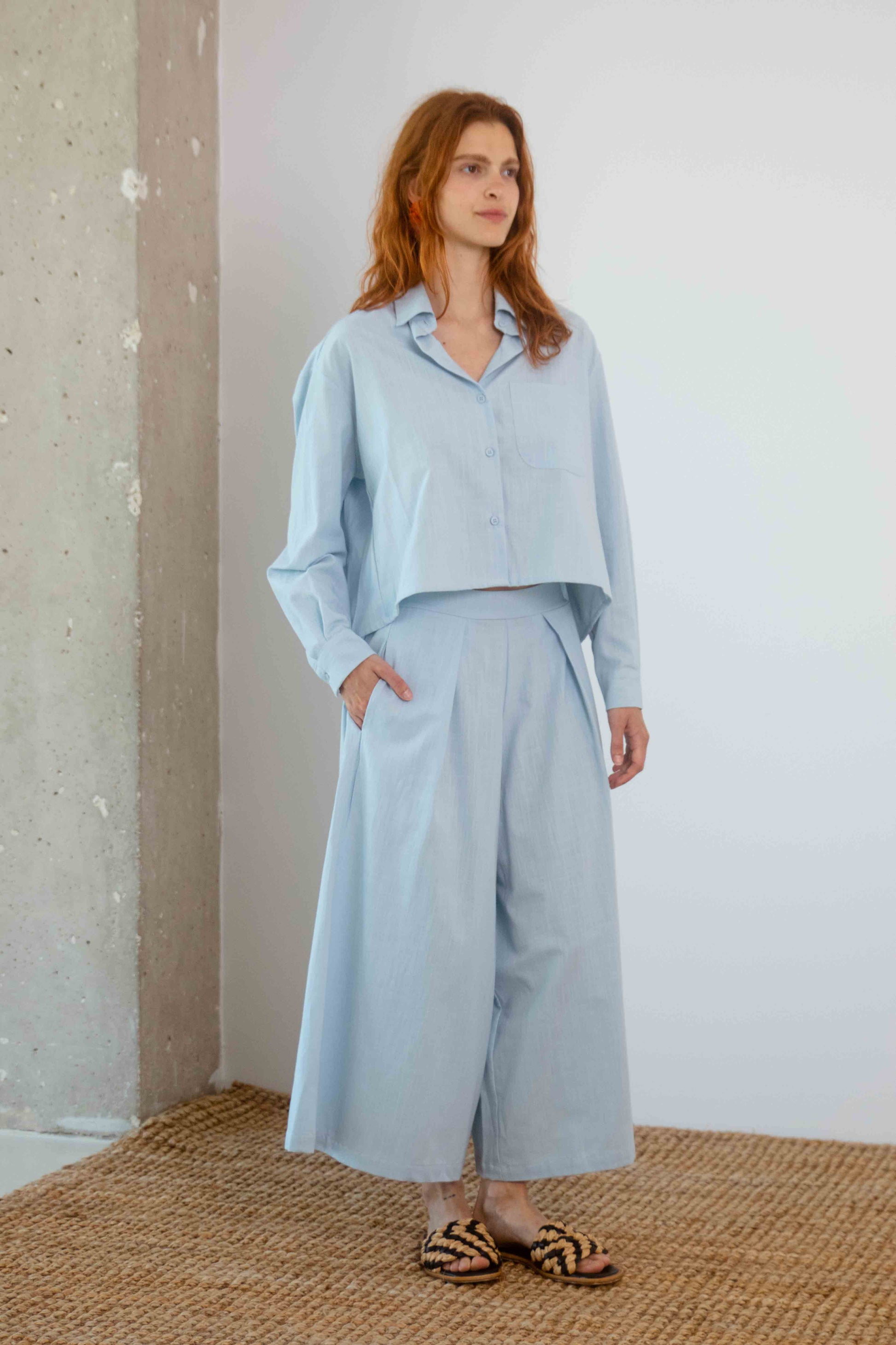 Organic Cotton Wide Culottes in Pale Blue worn with matching wide-leg pants in a modern, relaxed setting.