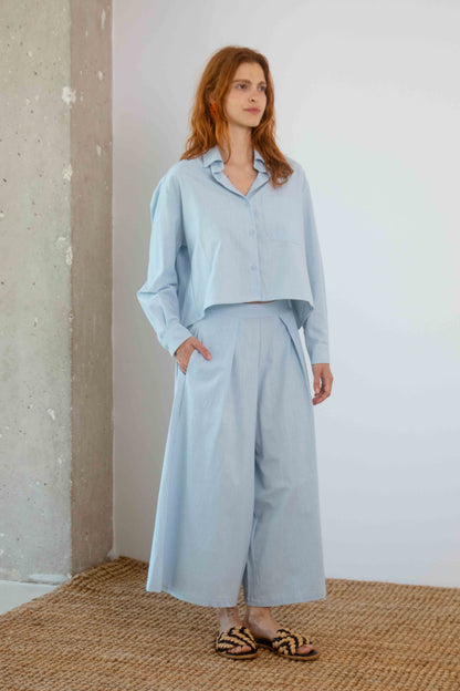 Organic Cotton Wide Culottes in Pale Blue worn with matching wide-leg pants in a modern, relaxed setting.