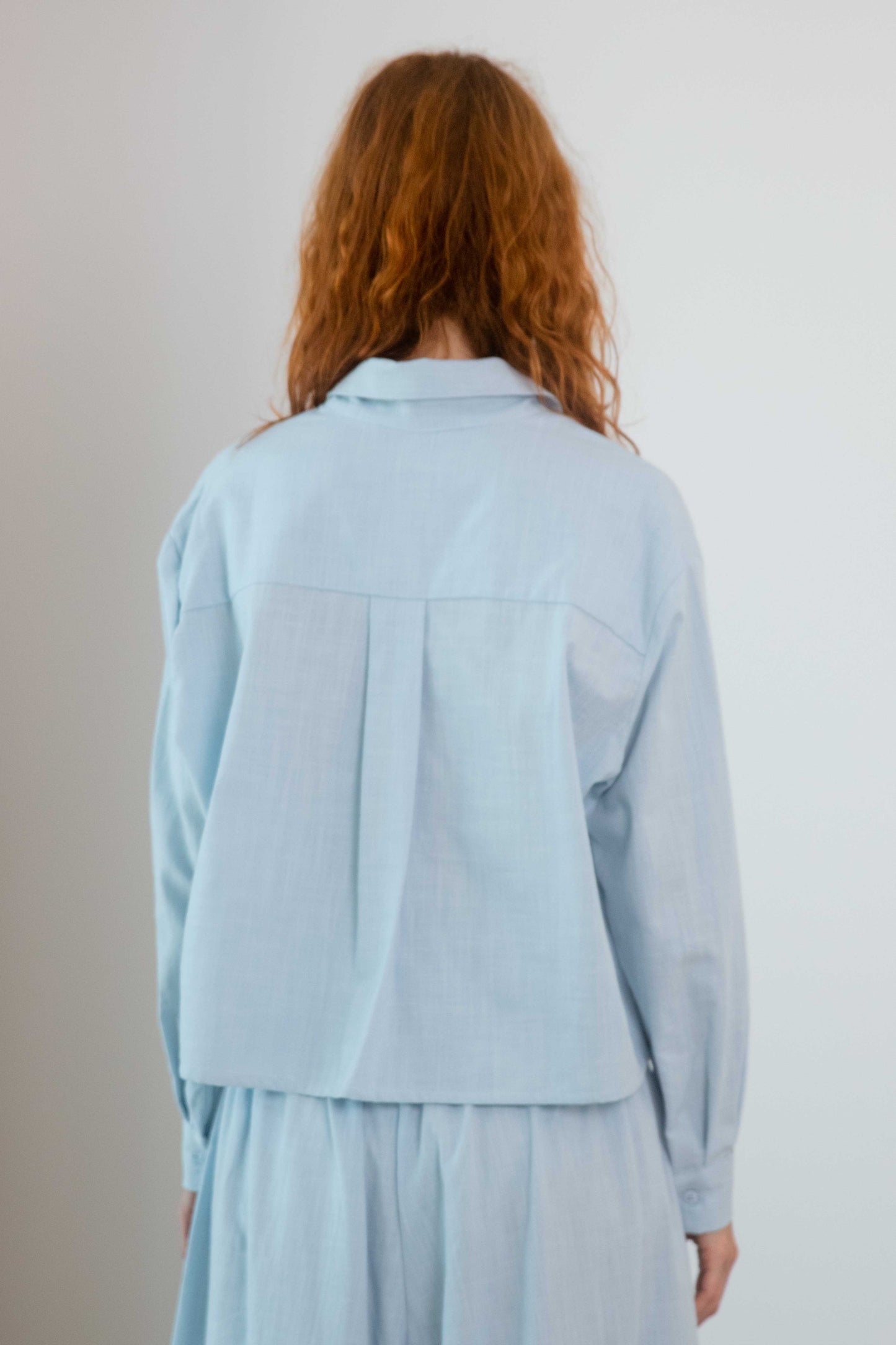 Cropped Organic Cotton Shirt in Pale Blue view from the back, showcasing the relaxed fit and lightweight fabric.