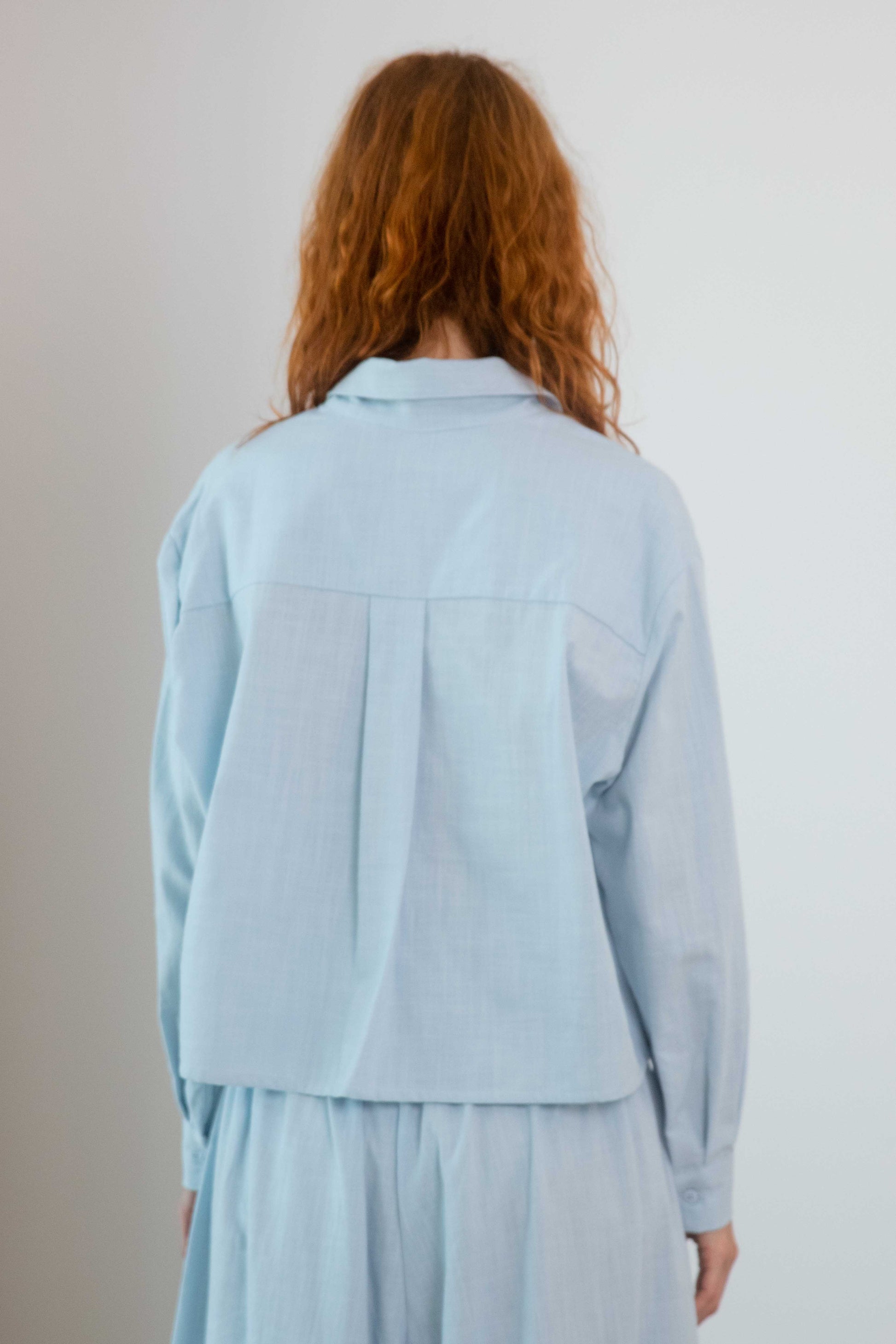 Cropped Organic Cotton Shirt in Pale Blue view from the back, showcasing the relaxed fit and lightweight fabric.