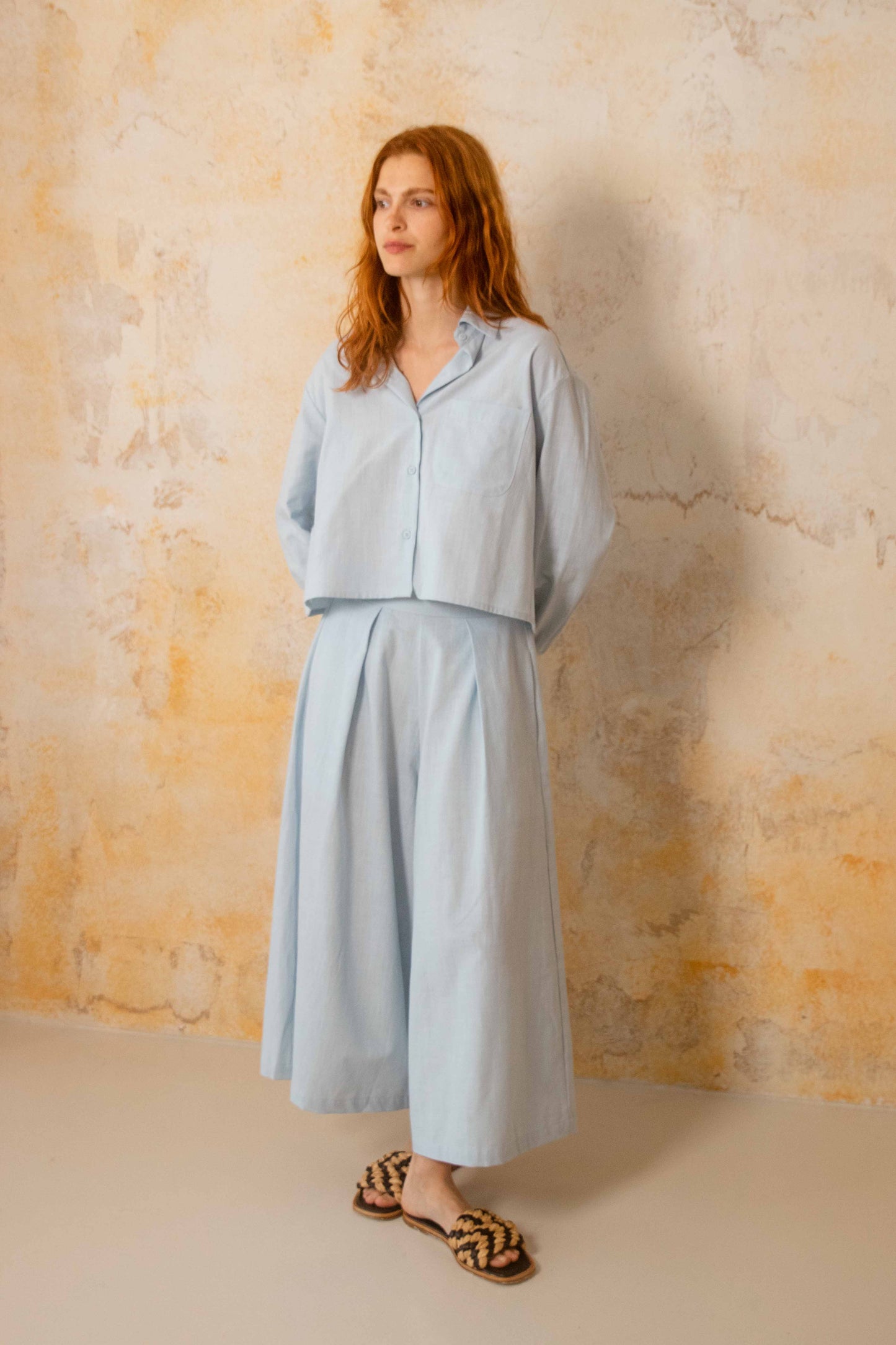 Cropped Organic Cotton Shirt in Pale Blue worn with matching skirt, showcasing relaxed spring-summer style.