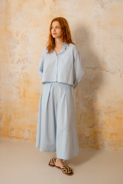 Cropped Organic Cotton Shirt in Pale Blue worn with matching skirt, showcasing relaxed spring-summer style.