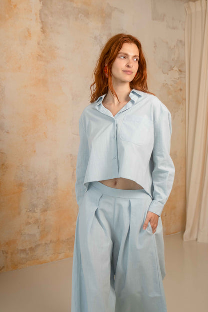Cropped Organic Cotton Shirt in Pale Blue worn with matching pants, featuring a relaxed fit and stylish design.