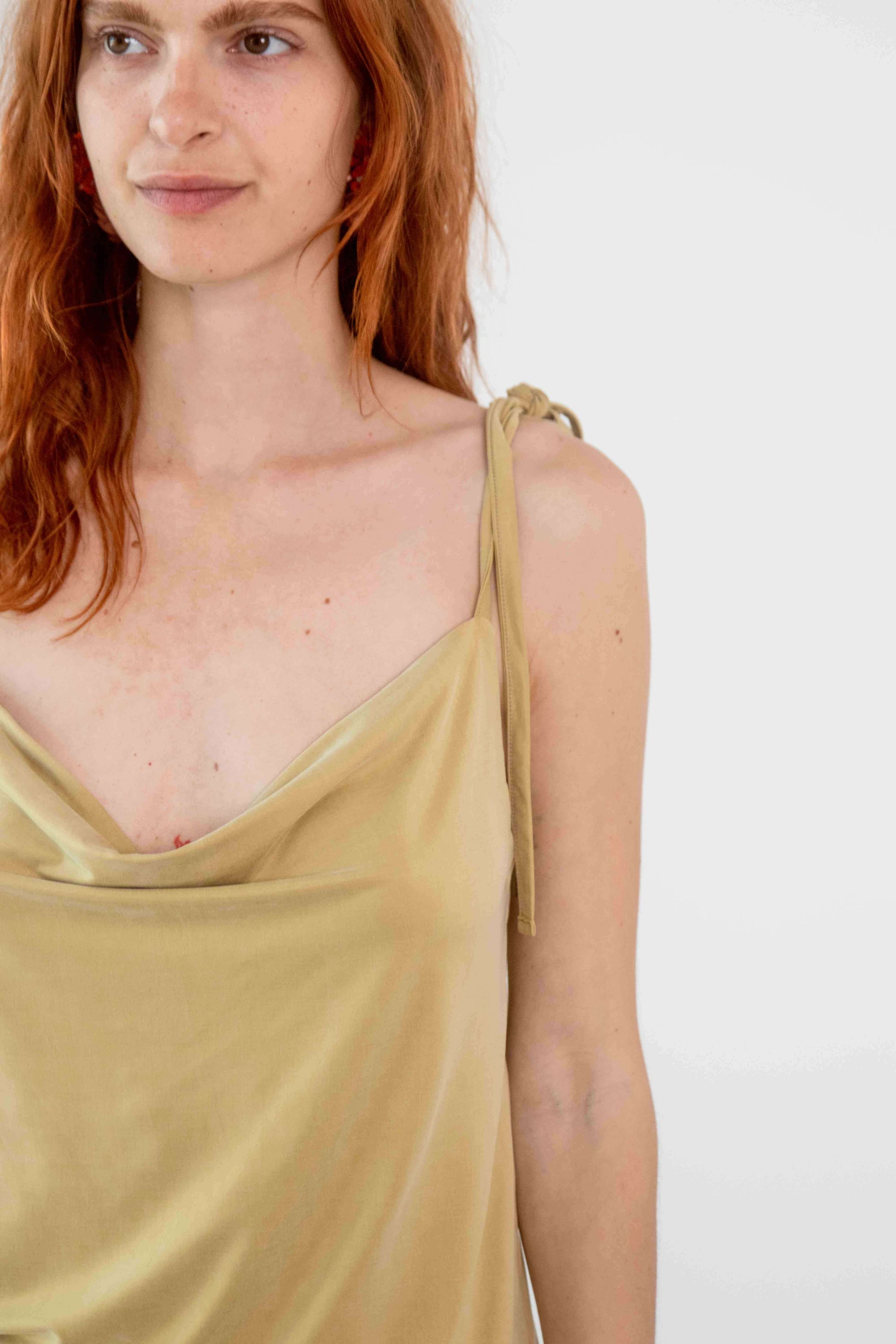 Model wearing Cupro Drape Slip Top in Soft Olive with adjustable straps and a flattering draped neckline.