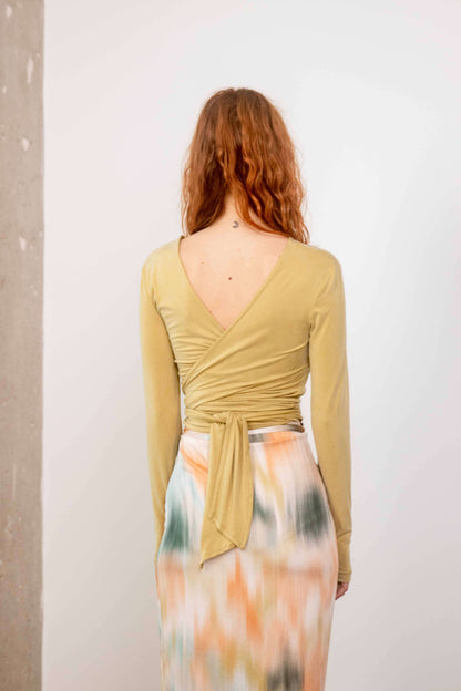 Cupro Multiway Wrap Top in Soft Olive, showing the back view with a stylish wrap design and a flowing skirt.