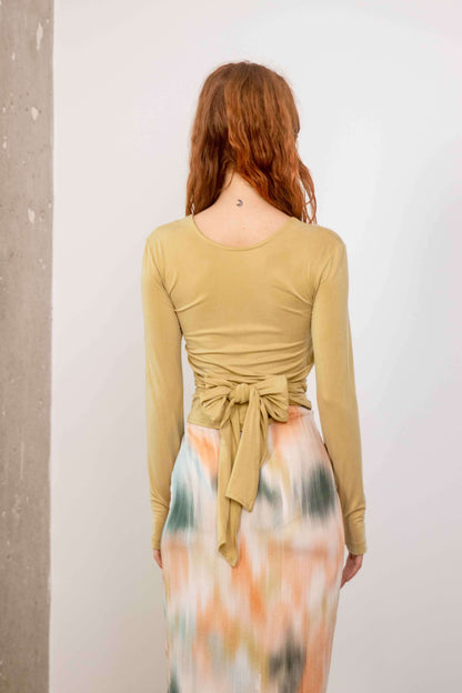 Model wearing the Cupro Multiway Wrap Top in Soft Olive, showing the back and tie detail.