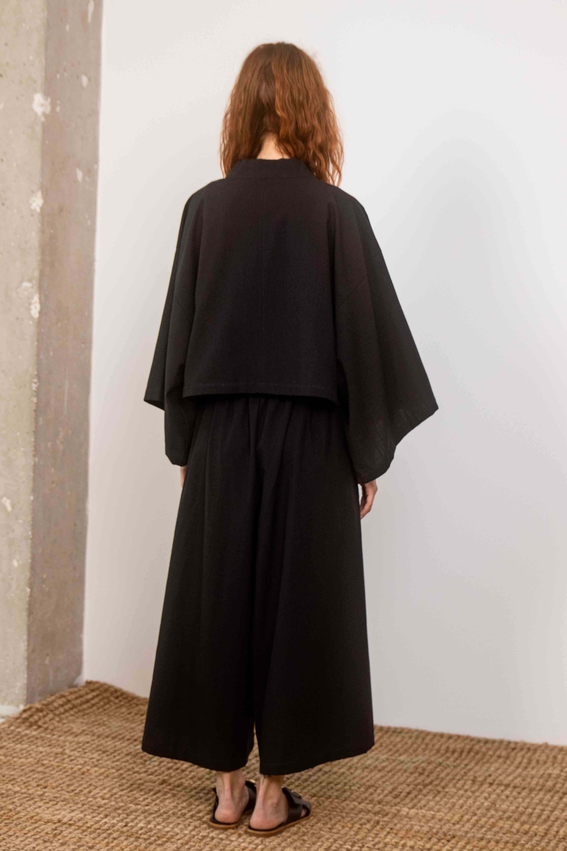 Organic Cotton Wide Culottes in Black worn from the back, showcasing a relaxed silhouette and modern style.