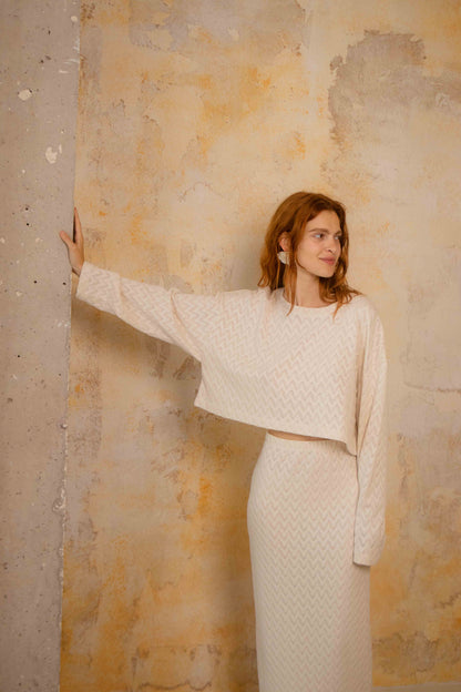 Model wearing a Crochet Organic Cotton Midi Skirt with a matching textured crop top against a vintage wall.