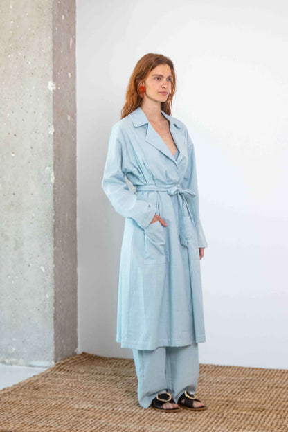 Lightweight Organic Cotton Trench Coat in Pale Blue worn by model, showcasing relaxed silhouette and detachable belt.