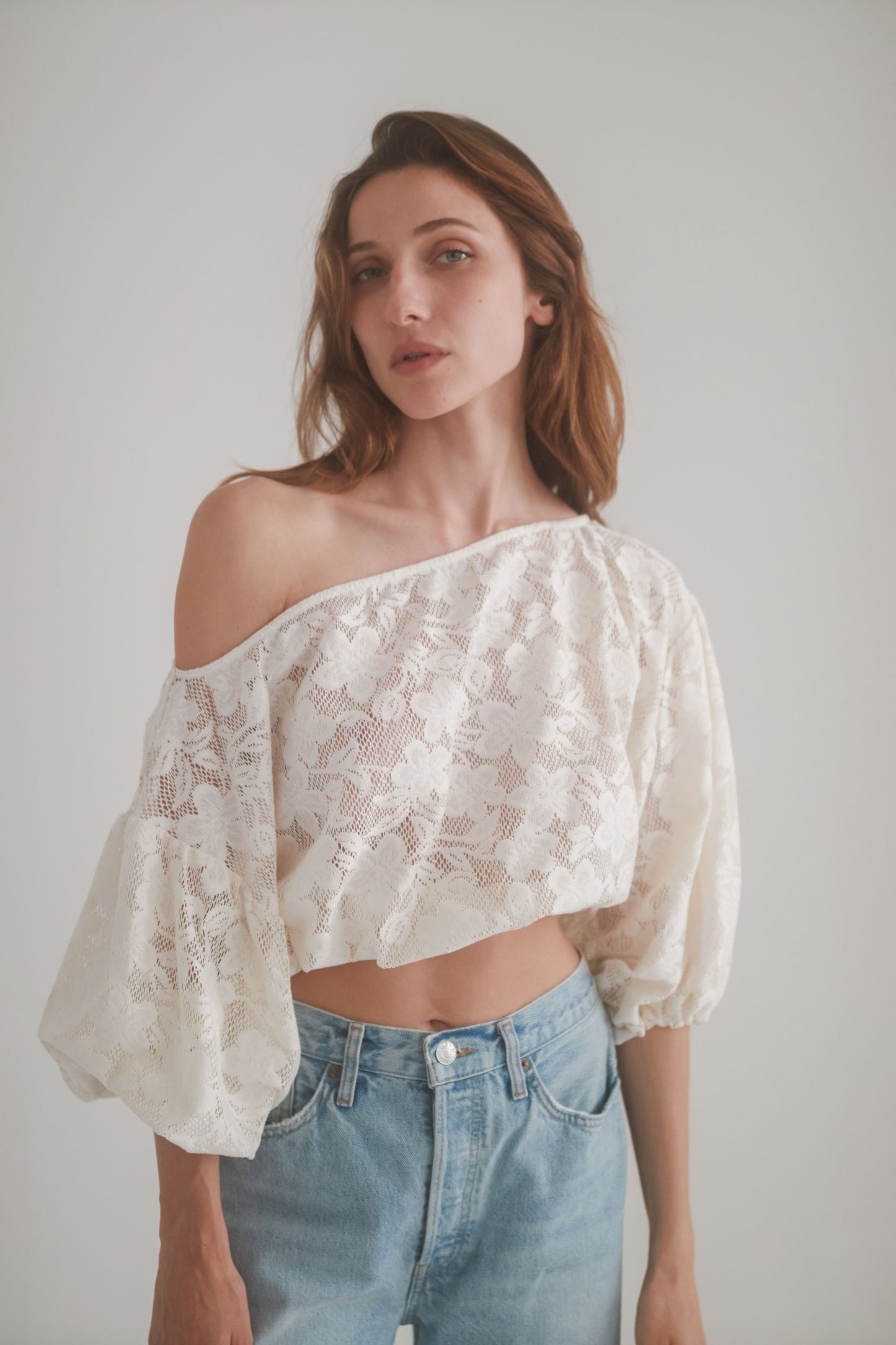 Elegant ecru lace boho blouse with balloon sleeves and off-shoulder design, paired with high-waisted jeans.