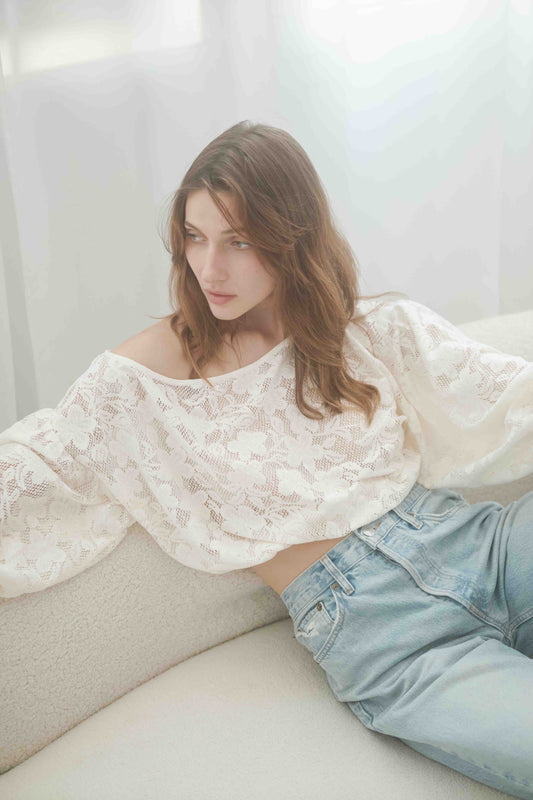 Model wearing an off-shoulder lace boho blouse with balloon sleeves, paired with light jeans, showcasing a chic and feminine style.
