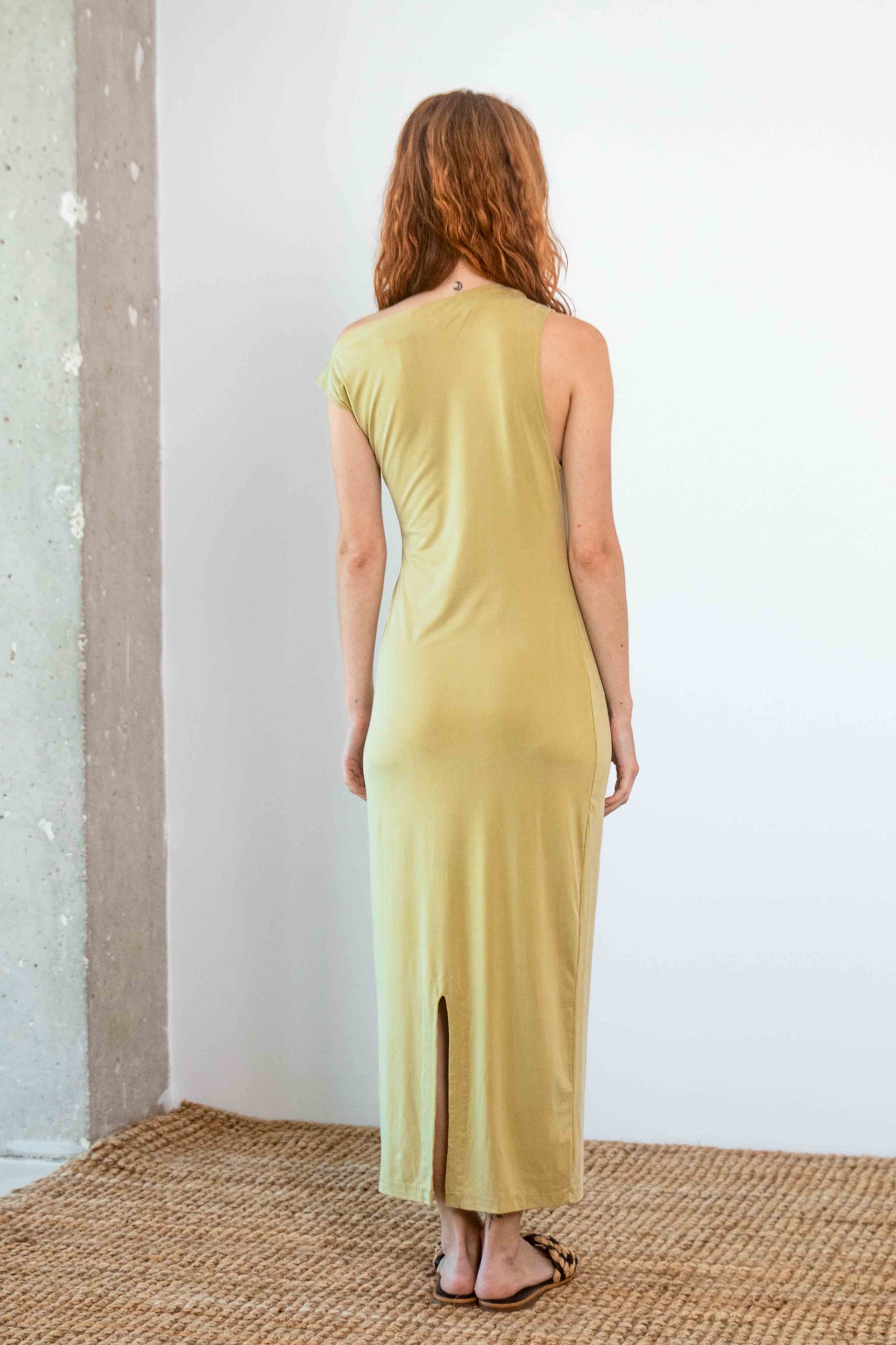 Drape Cupro Midi Dress in Olive displayed from the back, showcasing its sleek fit and slit detail.