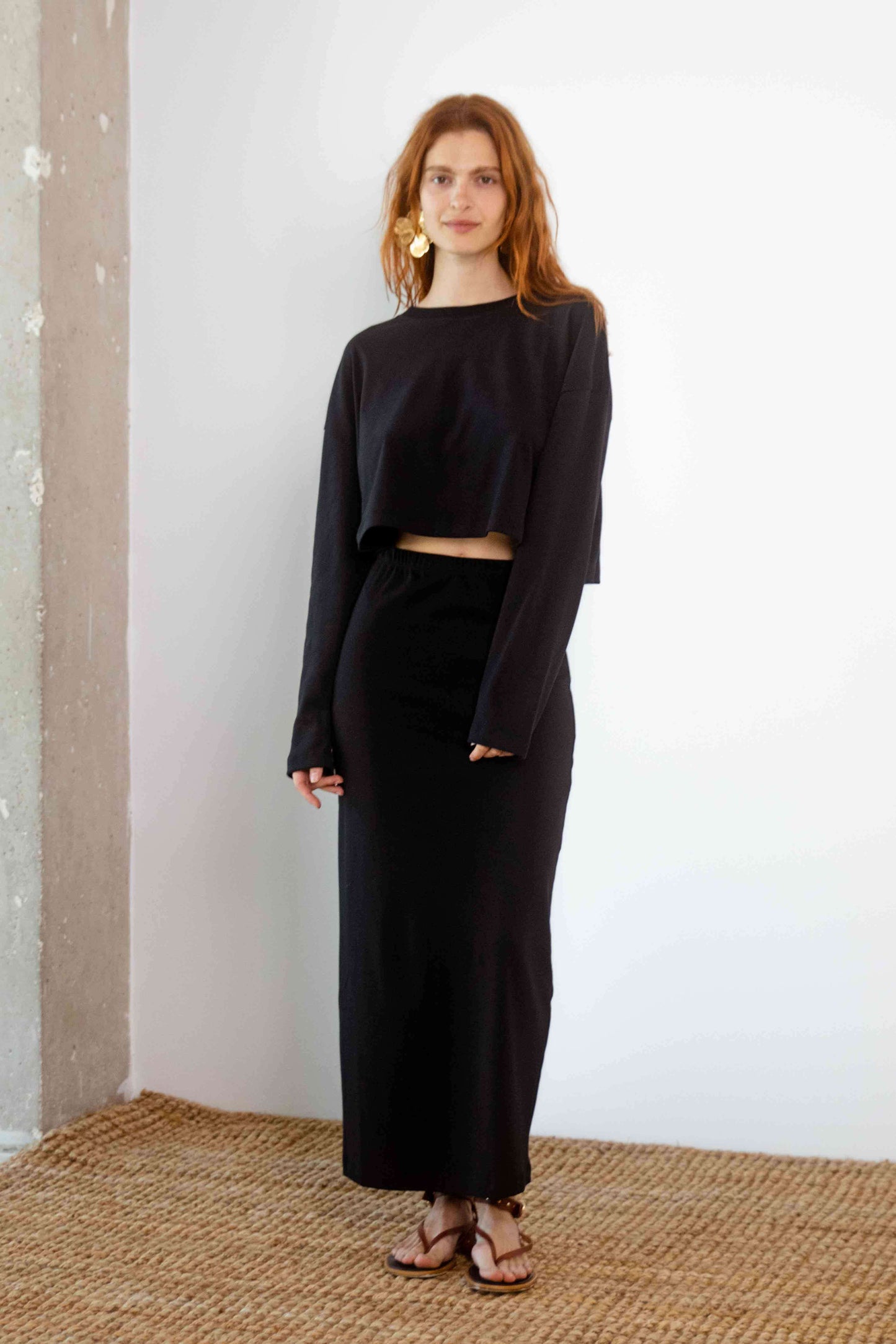 Model wearing Organic Cotton Midi Skirt in Black with a cropped black top, styled for modern spring-summer fashion.