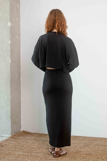 Model wearing Organic Cotton Midi Skirt in Black with a cropped top, showcasing a sleek back view.