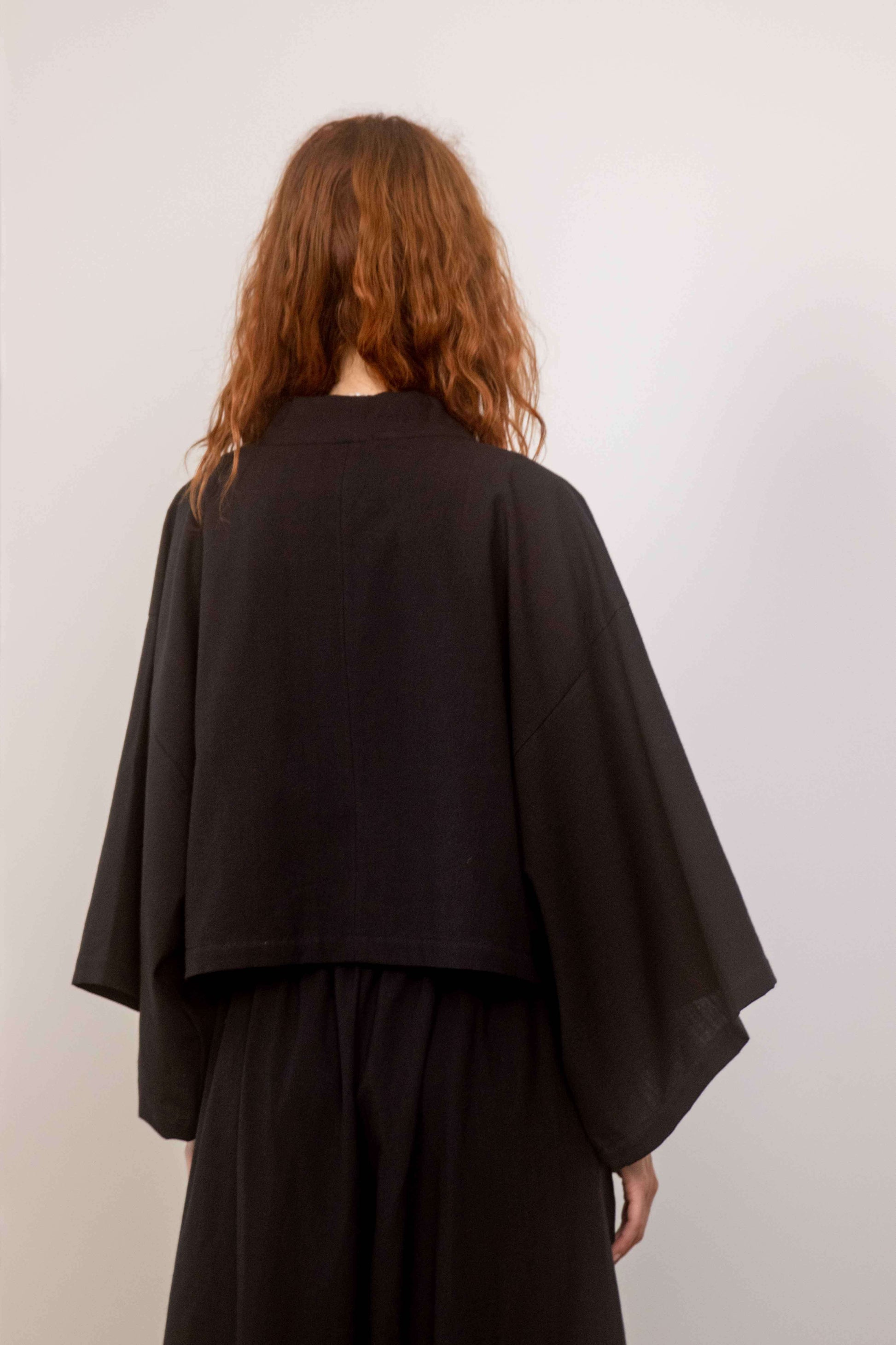 Back view of a woman wearing a Organic Cotton Kimono Jacket, showcasing its oversized, relaxed silhouette.