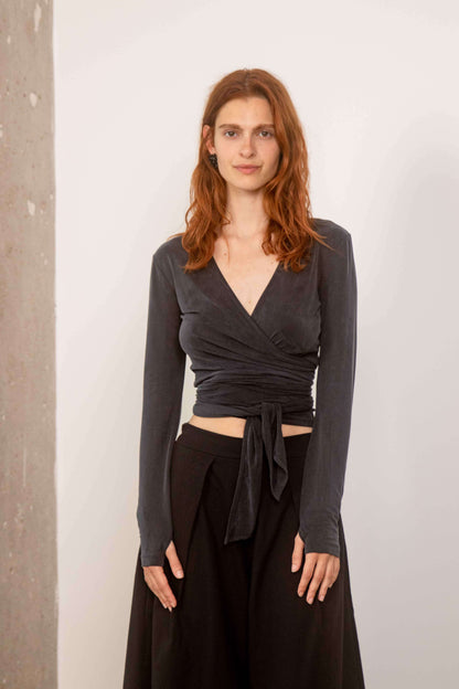 Model wearing Cupro Multiway Wrap Top  in Slate Black with long sleeves and wrap design.